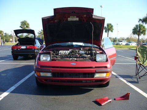 1991 Ford Probe - A red 1991 Ford Probe is parked with its hood open, revealing the engine, while another car is parked behind it.