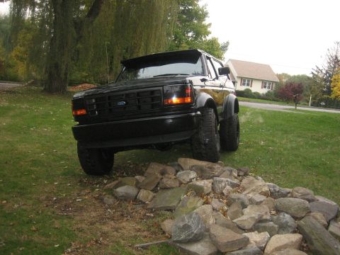 1995 Ford Bronco - This black 1995 Ford Bronco is presented with a lifted suspension and off-road tires, parked on a pile of rocks.