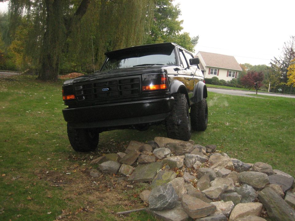 Black 1995 Ford Bronco with lifted suspension and off-road tires parked on rocks