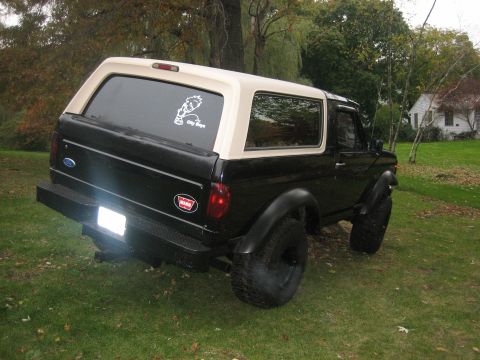 1995 Ford Bronco - This black and tan Ford Bronco is shown in a backyard setting.