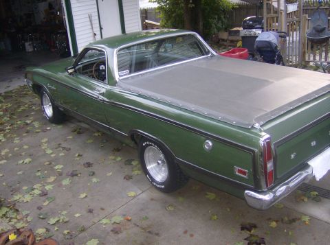 1970 Ford Ranchero - A green 1970 Ford Ranchero is parked outside a garage, covered with a grey tarp.