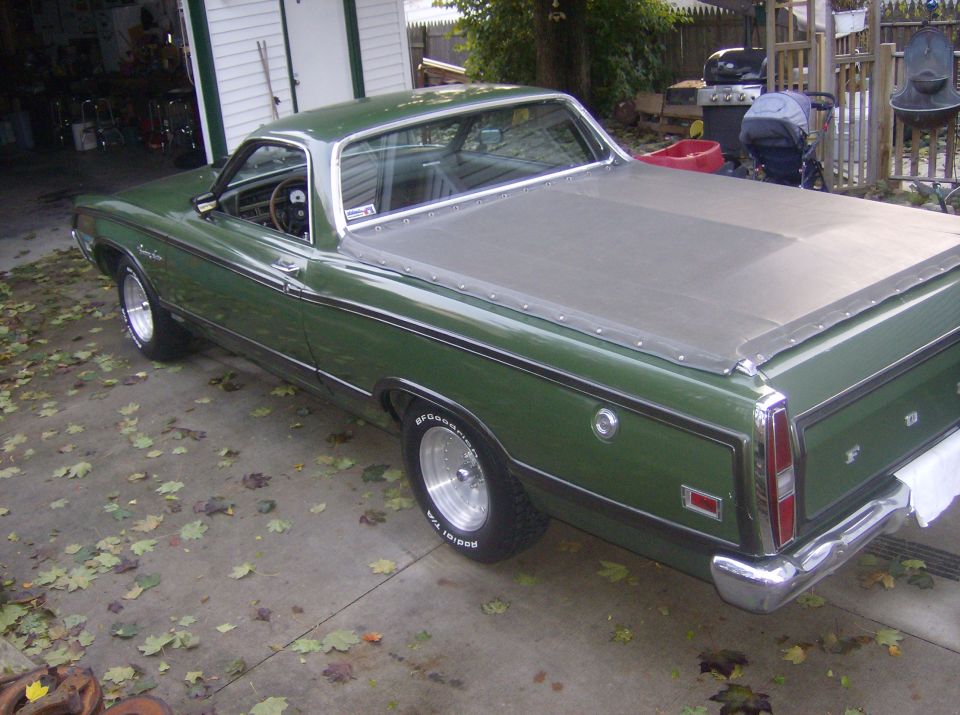 Dark green Ford Ranchero with tan tonneau cover and BFGoodrich tires in driveway