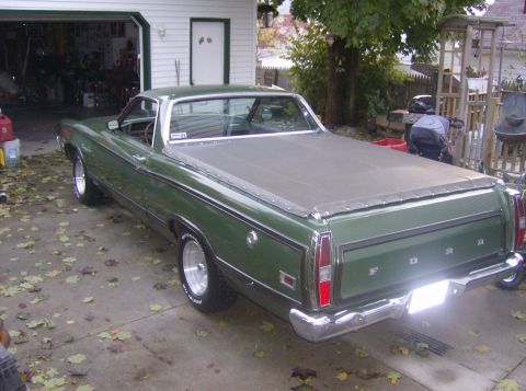 1970 Ford Ranchero - A green 1970 Ford Ranchero is parked in front of a garage, with fallen leaves on the ground.