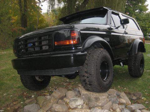 1995 Ford Bronco - This black 1995 Ford Bronco is shown with a lifted suspension, resting on a bed of rocks.