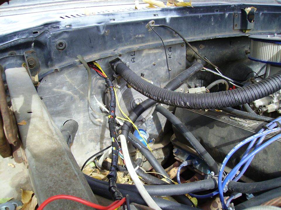 Engine bay wiring harness and hoses behind a vehicle radiator support