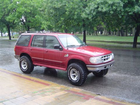 1996 Ford Explorer - This red SUV, likely a 1995 model, is equipped with off-road tires and appears to be modified.