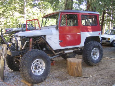 1986 Ford Bronco - A heavily modified Toyota Land Cruiser FJ40 is parked outdoors with its doors removed, hood, and fenders removed.