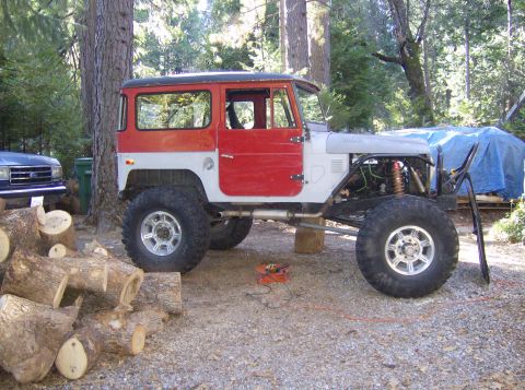 1986 Ford Bronco - This heavily modified Toyota Land Cruiser FJ40 is shown outdoors with a blue tarp and another vehicle in the background.