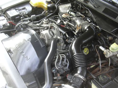 1997 Ford Crown Victoria - Close-up view of a clean engine bay, a black intake system and fan shroud with visible text.