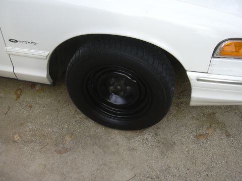 1997 Ford Crown Victoria - Close-up of the front fender and wheel of a white Ford Crown Victoria.