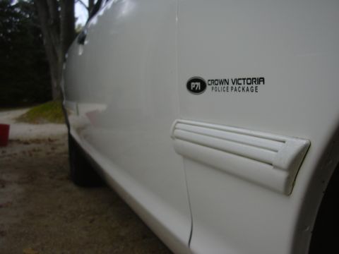 1997 Ford Crown Victoria - Close-up of a white police car door, the "Crown Victoria Police Package" badge and side trim.