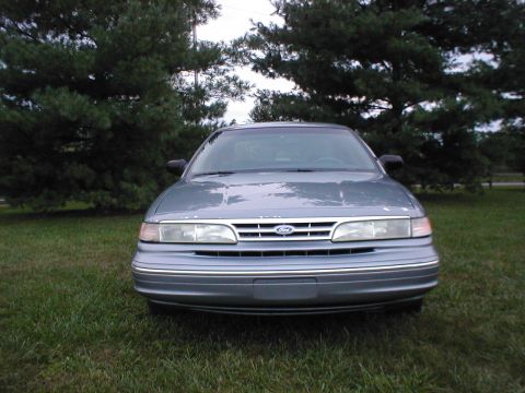 1997 Ford Crown Victoria - Front view of a gray 1997 Ford Crown Victoria parked on grass with trees in the background.