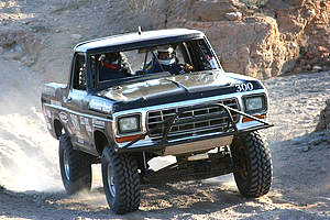 1978 Ford Bronco - Small action photo of a black square-body Ford Bronco race truck running a rocky desert course, shot three-quarter front with the front tir…