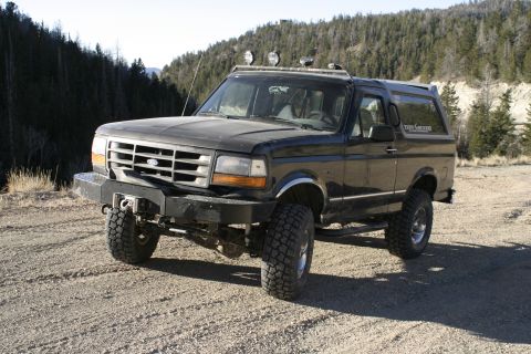 1994 Ford Bronco - A modified 1994 Ford Bronco sits on a dirt road, ready for off-road adventure.