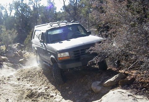 1994 Ford Bronco - 1994 Ford Bronco navigating a challenging off-road path.