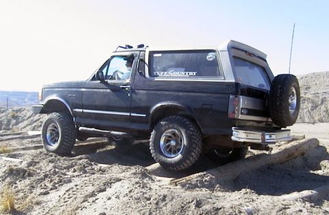 1994 Ford Bronco - This black Ford Bronco with silver trim is shown off-road with a spare tire mounted on the back.
