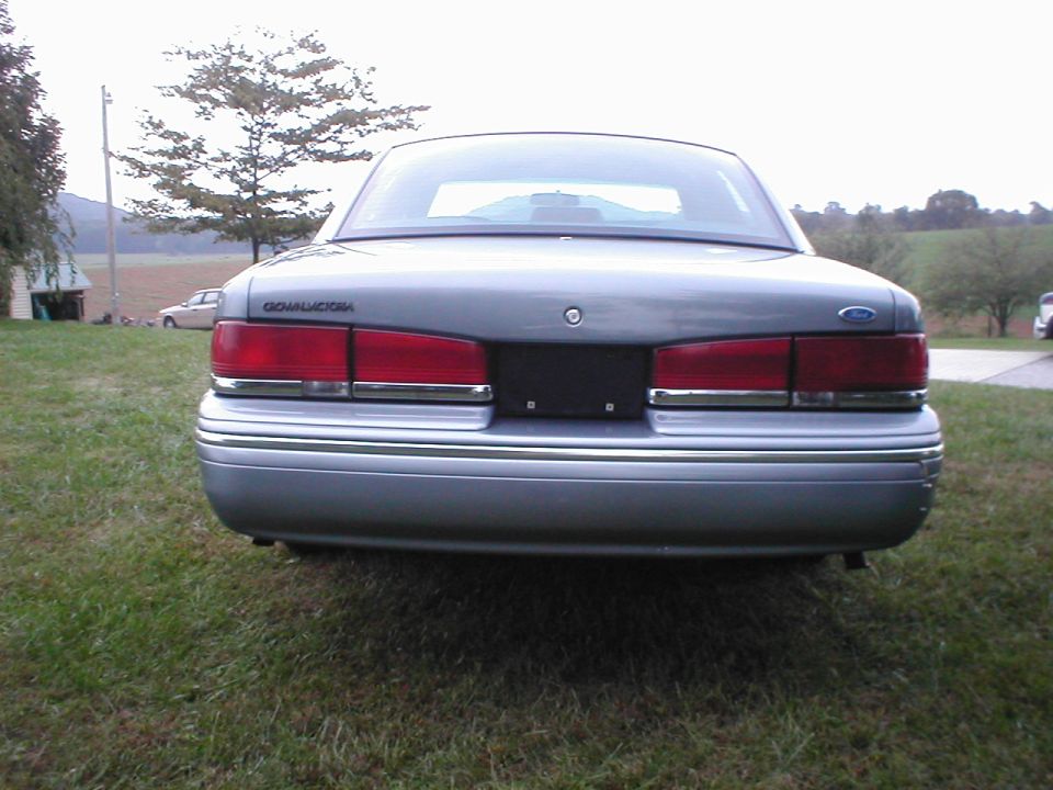 Rear of a silver Ford Crown Victoria sedan parked on grass