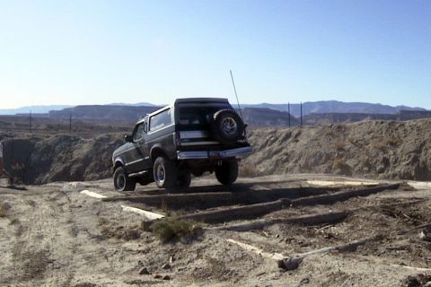 1994 Ford Bronco - A 1994 Ford Bronco navigates an off-road course with wooden beams on the ground.
