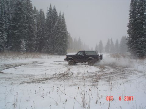 1994 Ford Bronco - A 1994 Ford Bronco navigates a snowy landscape, kicking up snow as it drives.