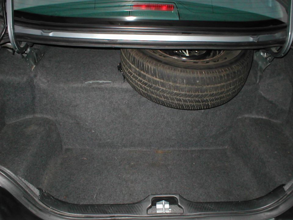 Sedan trunk interior with gray carpet and upright full-size spare on black steel wheel