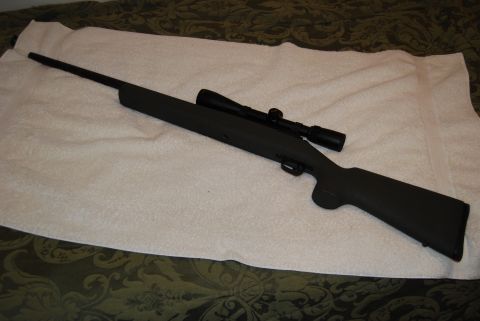 1991 Ford Bronco - A rifle with a scope is displayed on a towel, with a patterned fabric visible beneath.