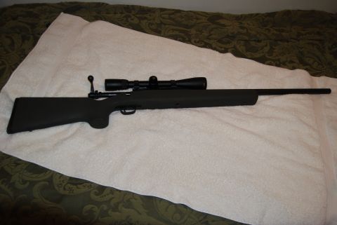 1991 Ford Bronco - A scoped rifle is displayed on a white surface with a patterned blanket in the background.