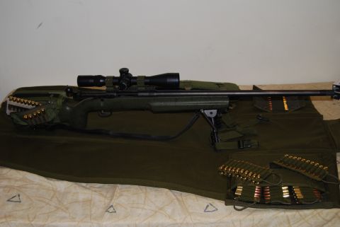 1991 Ford Bronco - A rifle with a scope and bipod is laid out with several clips of ammunition on a green mat.