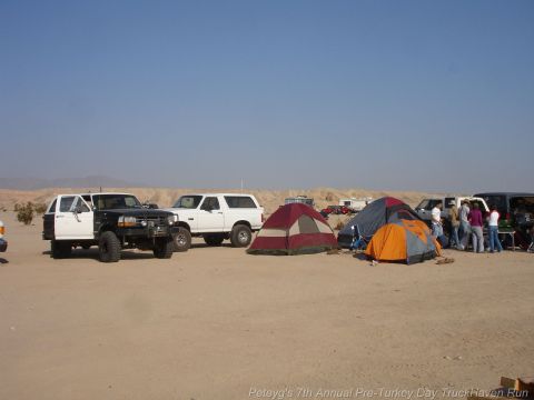 1994 Ford Bronco - Desert camping scene with multiple off-road vehicles and tents under a clear blue sky.
