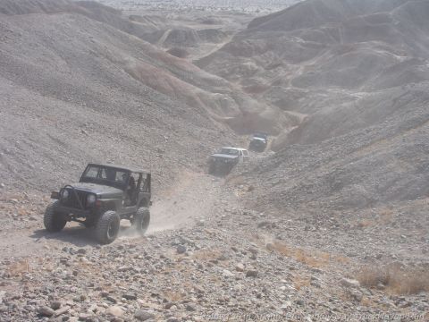 1994 Ford Bronco - A group of Jeeps navigates a desert canyon, kicking up dust on the trail.