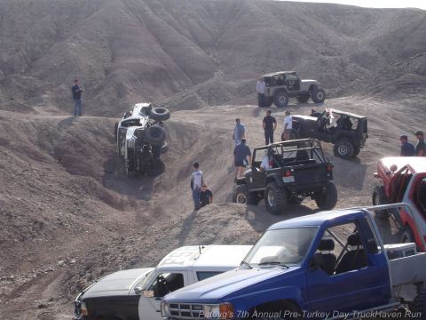 1994 Ford Bronco - A group of off-road vehicles navigates a challenging desert landscape, with one vehicle having flipped over.