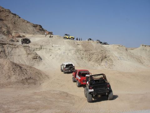 1994 Ford Bronco - A group of off-road vehicles navigates a sandy trail in a desert landscape.