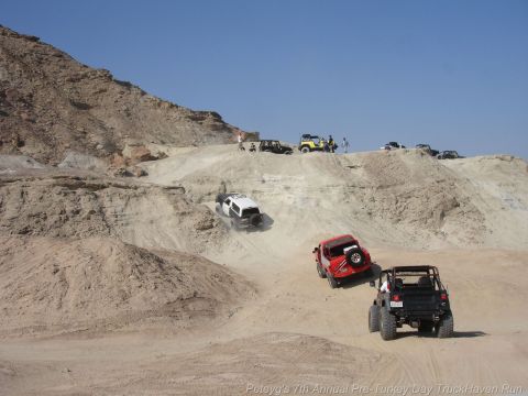 1994 Ford Bronco - Off-road vehicles descend a challenging sandy slope during an event.
