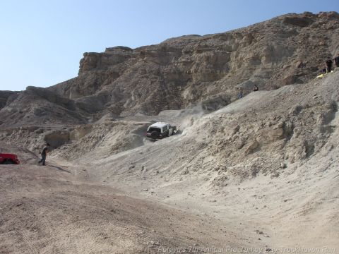 1994 Ford Bronco - Off-road vehicles navigate a challenging, arid terrain under a clear blue sky.