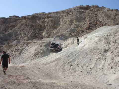 1994 Ford Bronco - A white SUV navigates a steep, dusty incline in a rocky, desert-like environment.