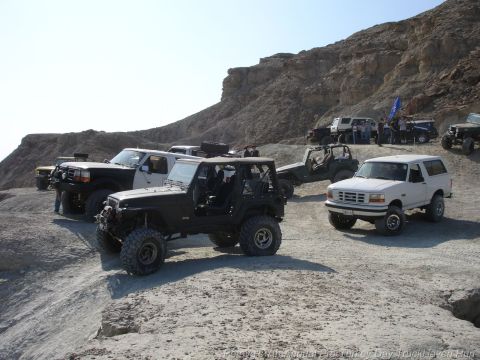 1994 Ford Bronco - Several off-road vehicles are parked on a dusty, rocky incline under a clear sky.