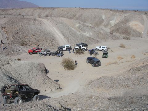 1994 Ford Bronco - Multiple off-road vehicles are parked and driving in a desert landscape, suggesting an organized event or trail ride.