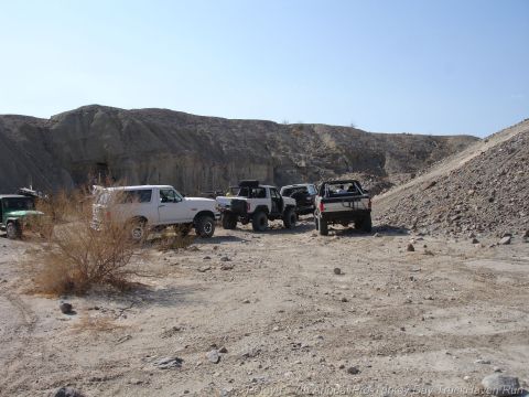 1994 Ford Bronco - A group of off-road vehicles gathered in a rocky desert area under a clear blue sky.