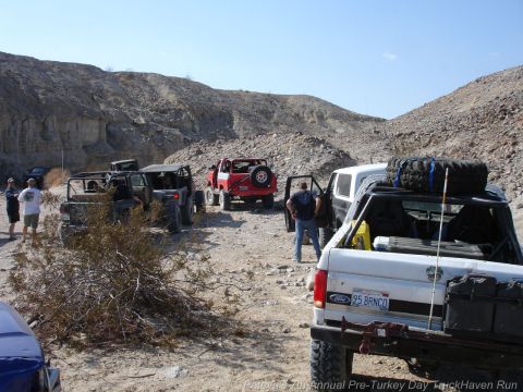 1994 Ford Bronco - Several off-road vehicles, including a white 1995 Ford Bronco, are parked in a desert landscape.