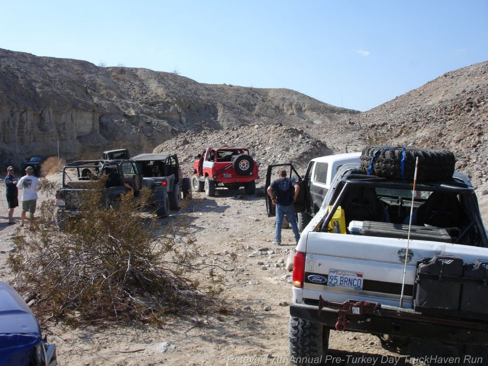 White 1995 Ford Bronco rear view, license plate '95 BRNCO', spare tire on roof rack, off-road modifications