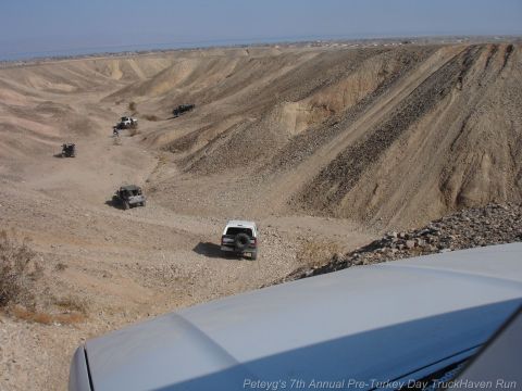 1994 Ford Bronco - Multiple SUVs and trucks navigate a , dusty canyon terrain under a clear sky.