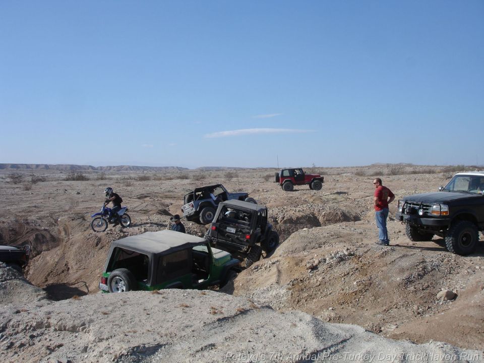 Black Ford F-150 truck with a brush guard parked on a dirt mound, facing right