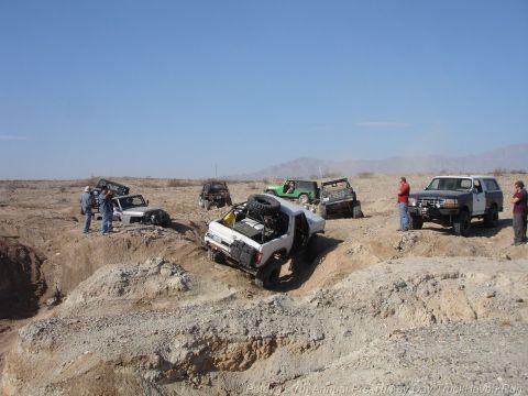 1994 Ford Bronco - Several off-road vehicles, including a 1994 Ford Bronco, navigate a challenging desert terrain.