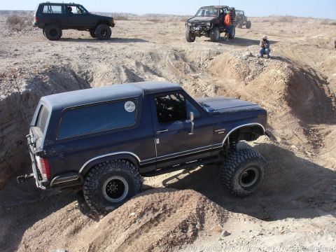 1994 Ford Bronco - Modified Ford Bronco tackles a challenging off-road course with other vehicles present.