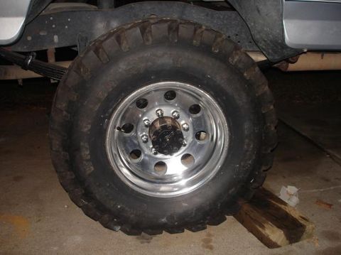 1996 Ford F-150 - A close-up view of a large truck tire and its suspension system, with a portion of the vehicle's body visible.