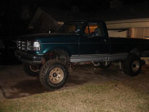 1996 Ford F-150 - A lifted 1996 Ford F-150 pickup truck is parked in a driveway at night.