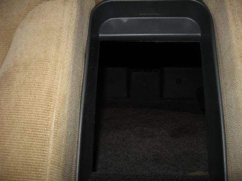 1992 Ford Crown Victoria - The open storage compartment in the center console of a car is shown, with textured tan upholstery on the side.