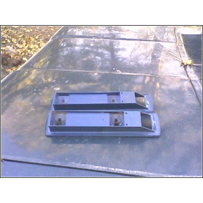 1973 Ford Ranchero - Two blue tail light housings are placed on a weathered green surface, possibly a car hood.