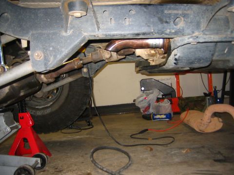 2001 Jeep Wrangler - Close-up of vehicle undercarriage, focusing on exhaust components and repair equipment.