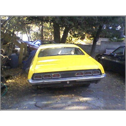1971 Mercury Cyclone - Rear view of a yellow coupe with horizontal taillights, parked near other vehicles.