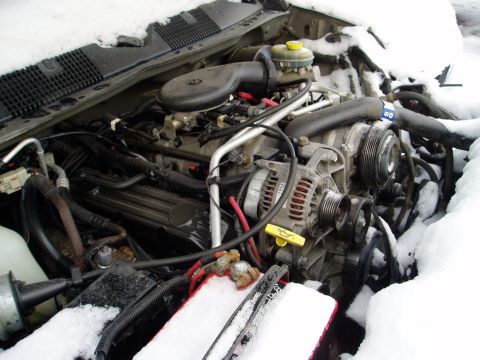 2000 Ford E350 - Vehicle engine bay partially obscured by snow, with visible engine components and battery.